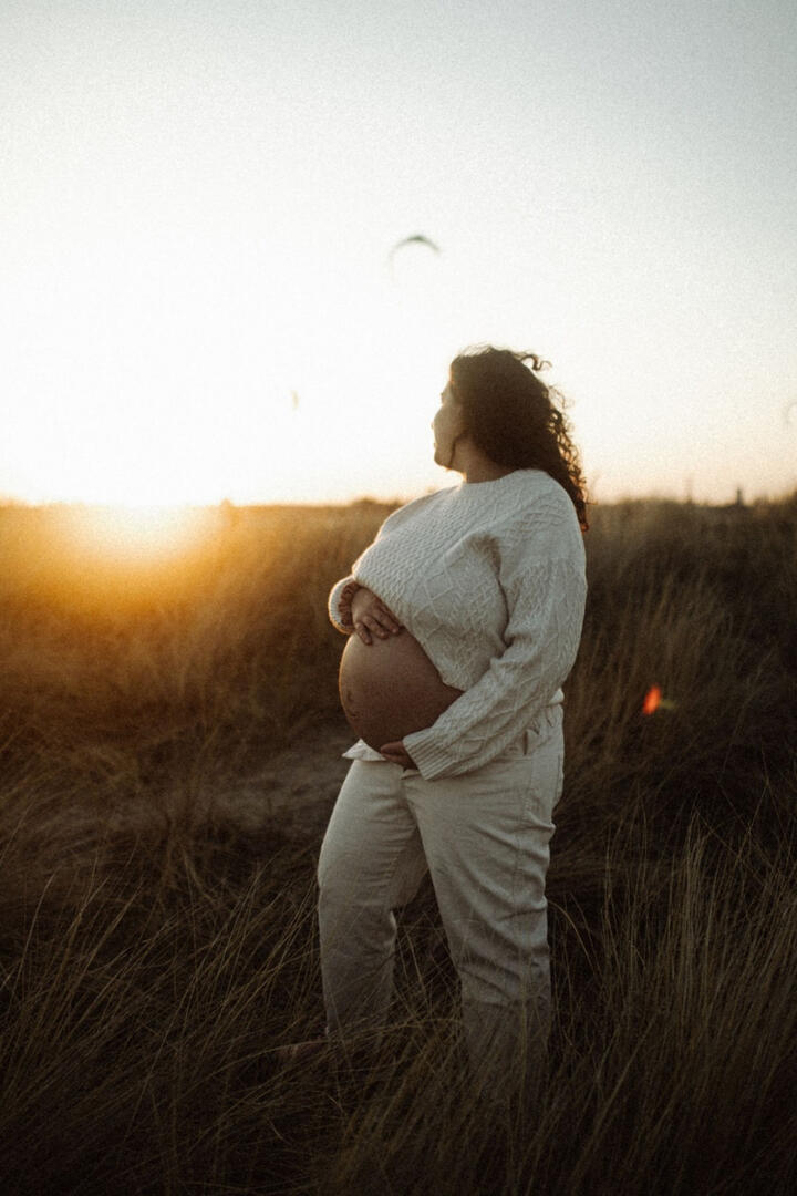 Ilena, pregnant, in the dune grass at sunset